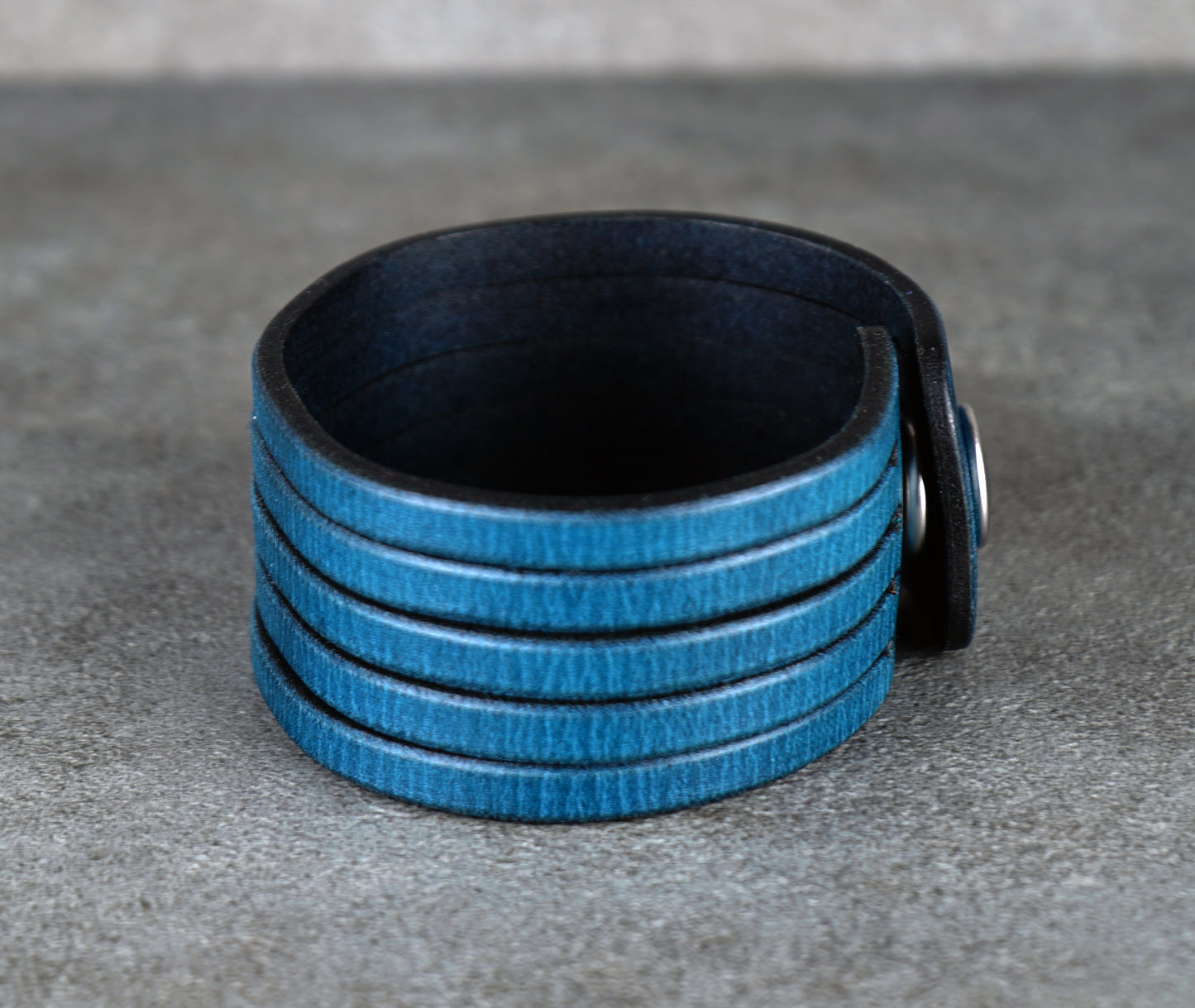 Blue leather bracelet on a gray surface