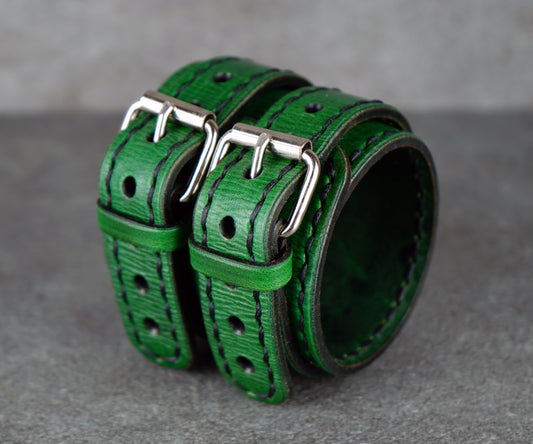 Green leather straps with silver buckles on a gray background