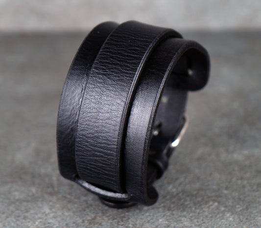 Black leather bracelet on a gray surface