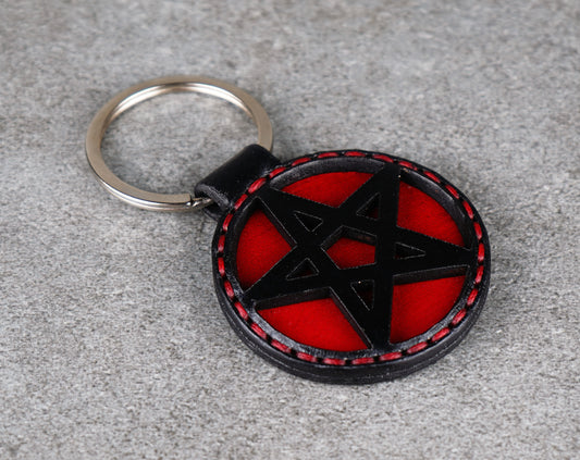Keychain with black pentagram design on a red background, attached to a keyring.