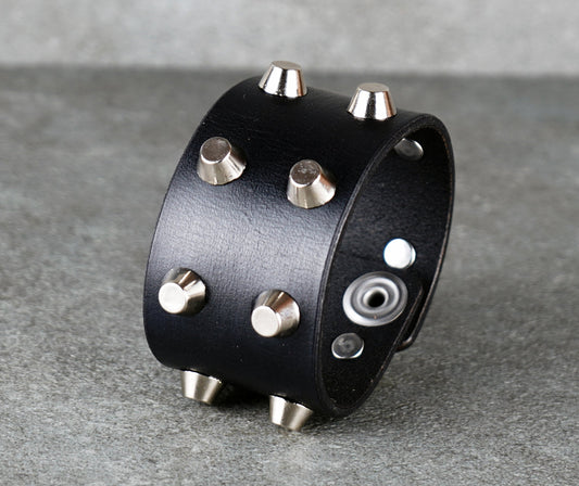 Black leather cuff with silver studs on a gray surface