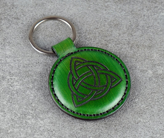 Green leather keychain with Celtic knot design on a gray surface