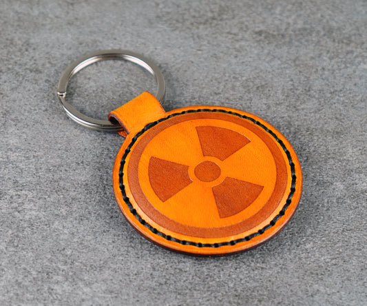 Yellow leather keychain with radiation symbol on a gray surface