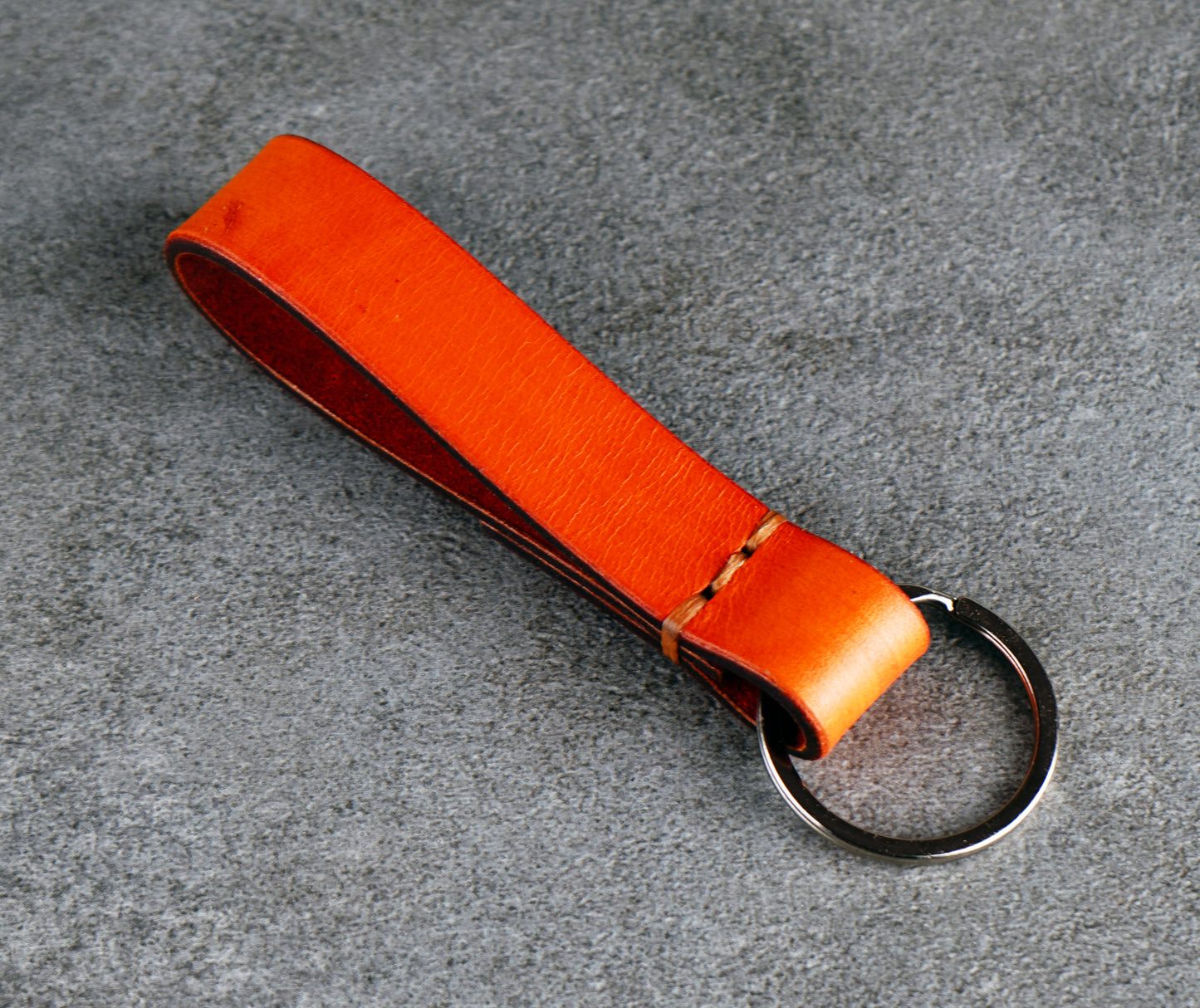 Orange leather key fob on a gray surface