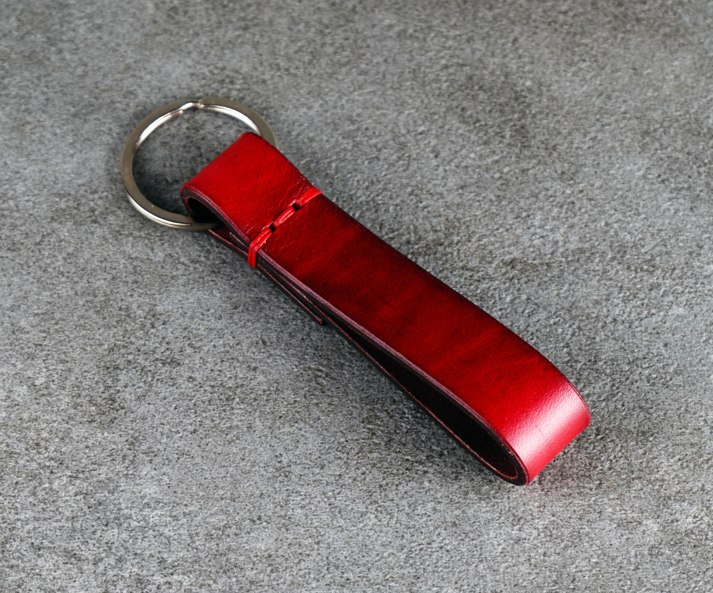 Red leather keychain on a gray surface