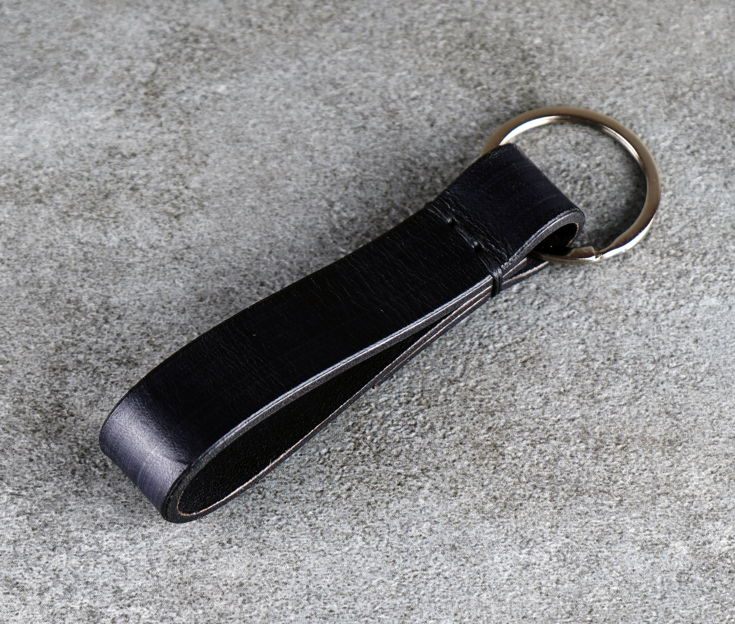 Black leather key fob on a gray concrete surface