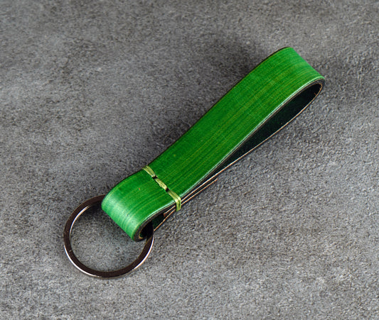 Green leather keychain on a gray surface
