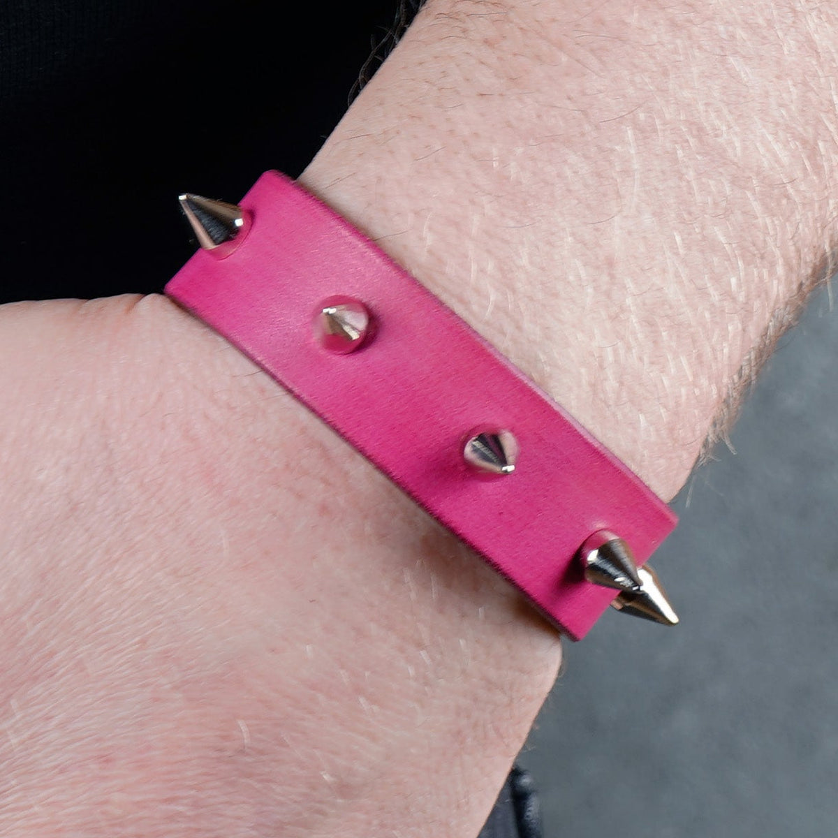 Pink spiked bracelet worn on a wrist from a close angled view