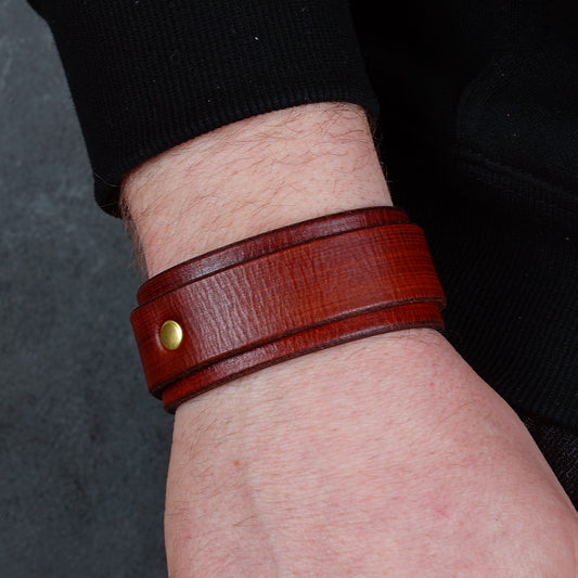 Brown leather cuff bracelet shown on a wrist from the side, highlighting the brass buckle