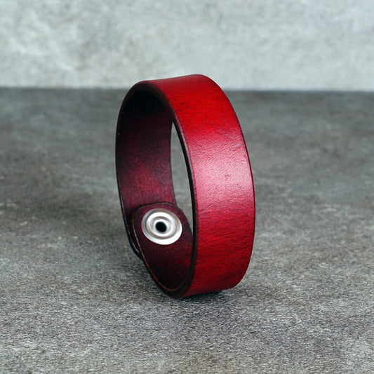 Red leather cuff bracelet standing upright with the snap closure facing forward