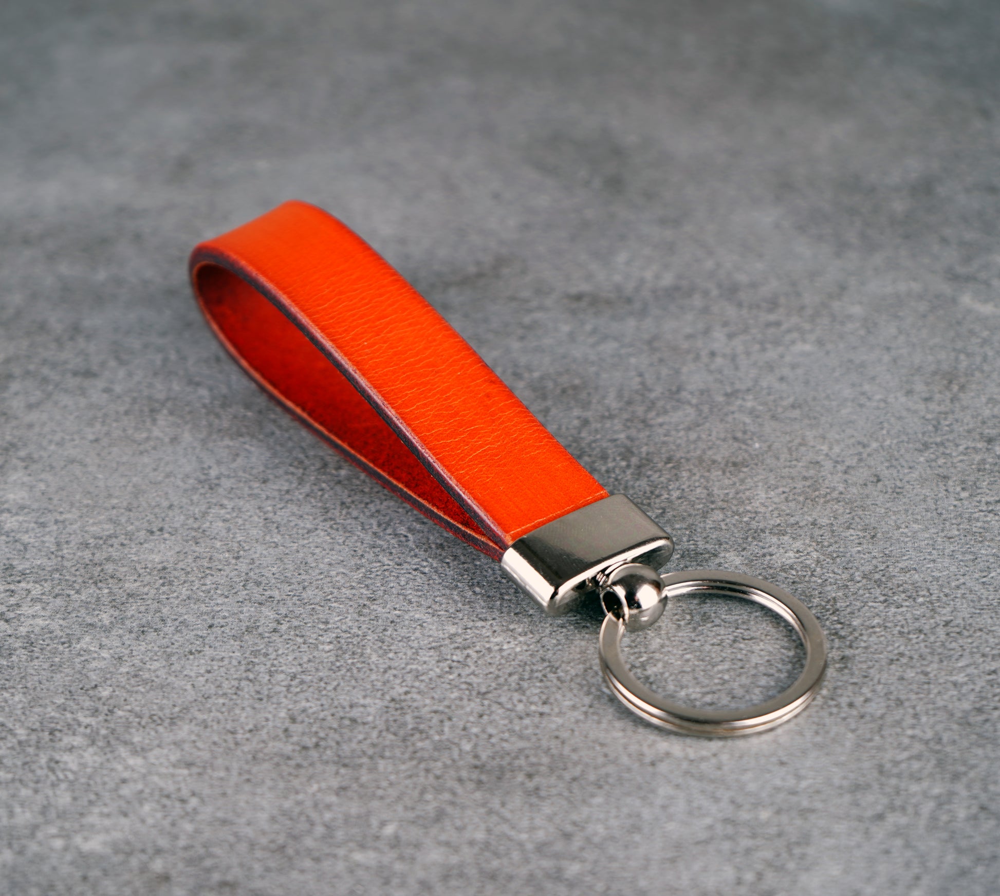 Orange leather keychain with a metal ring on a gray surface