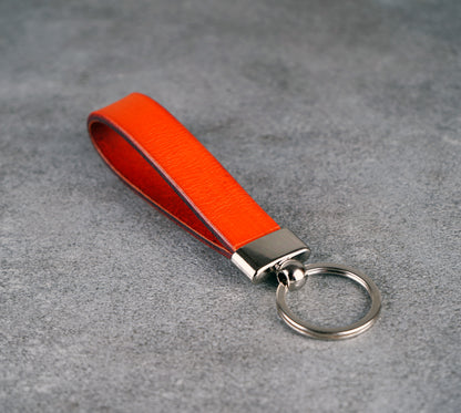 Orange leather keychain with a metal ring on a gray surface