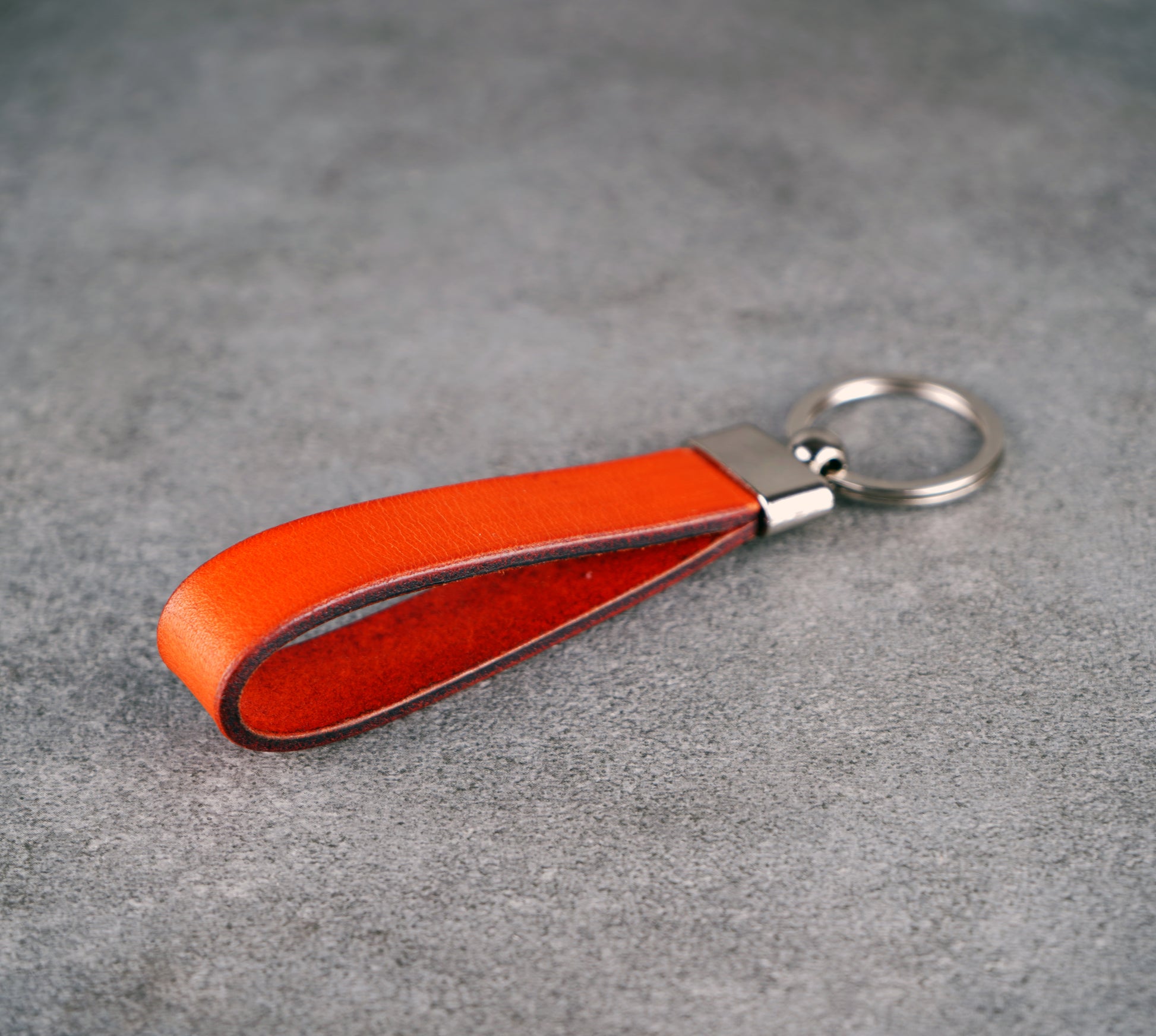 Orange leather keychain on a gray surface