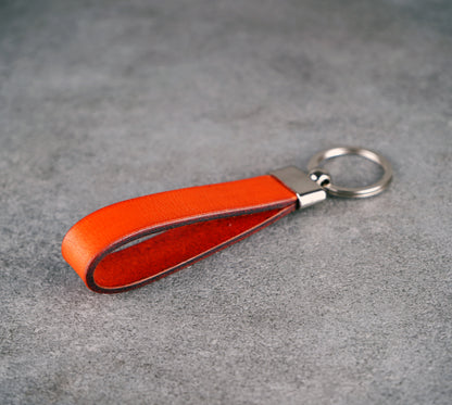 Orange leather keychain on a gray surface