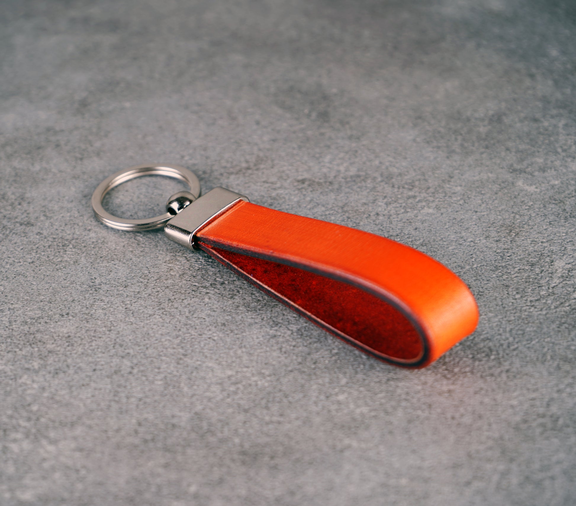 Orange leather keychain on a gray surface