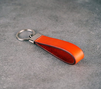 Orange leather keychain on a gray surface