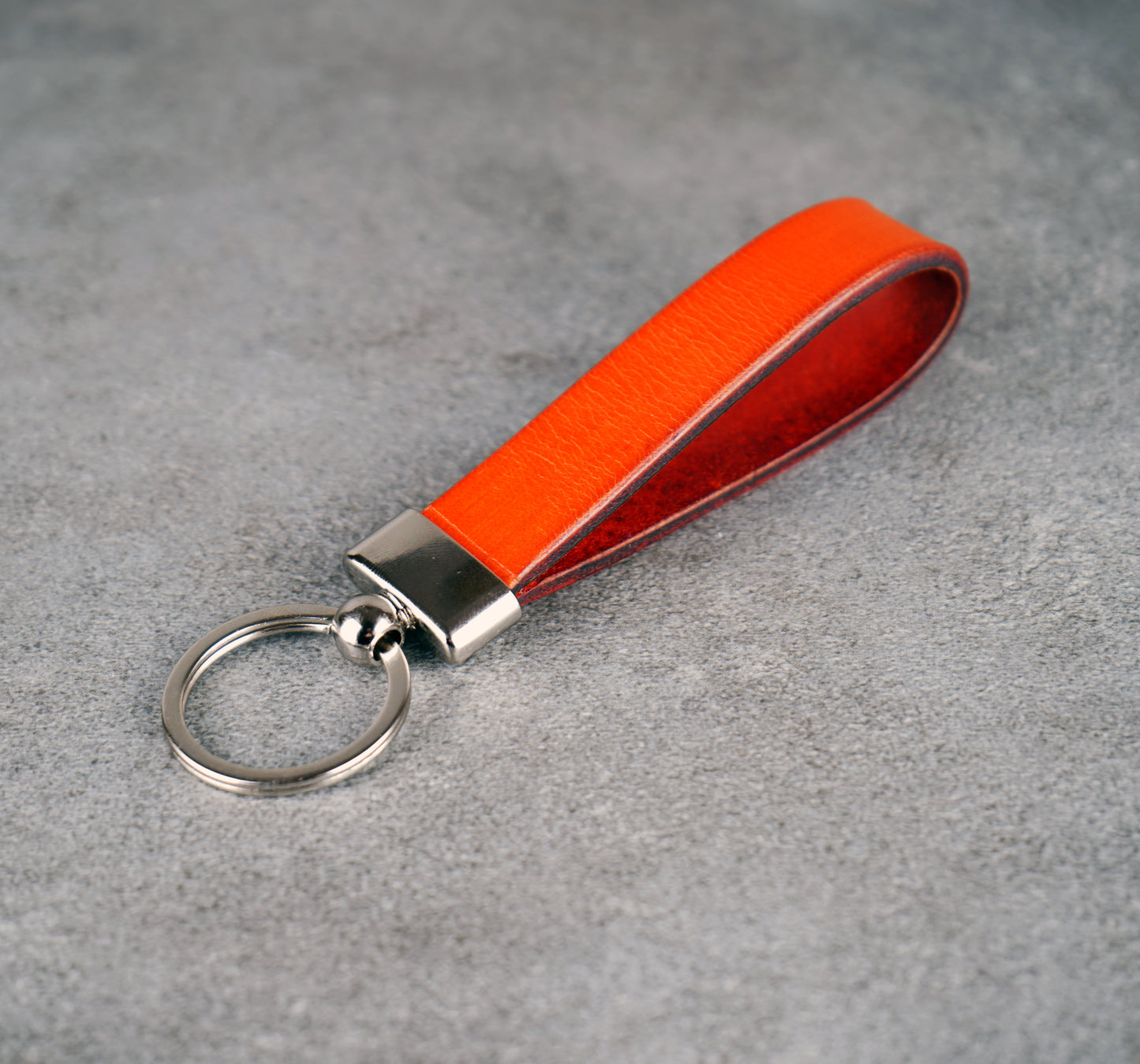 Orange leather keychain with a metal ring on a gray surface