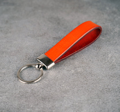 Orange leather keychain with a metal ring on a gray surface