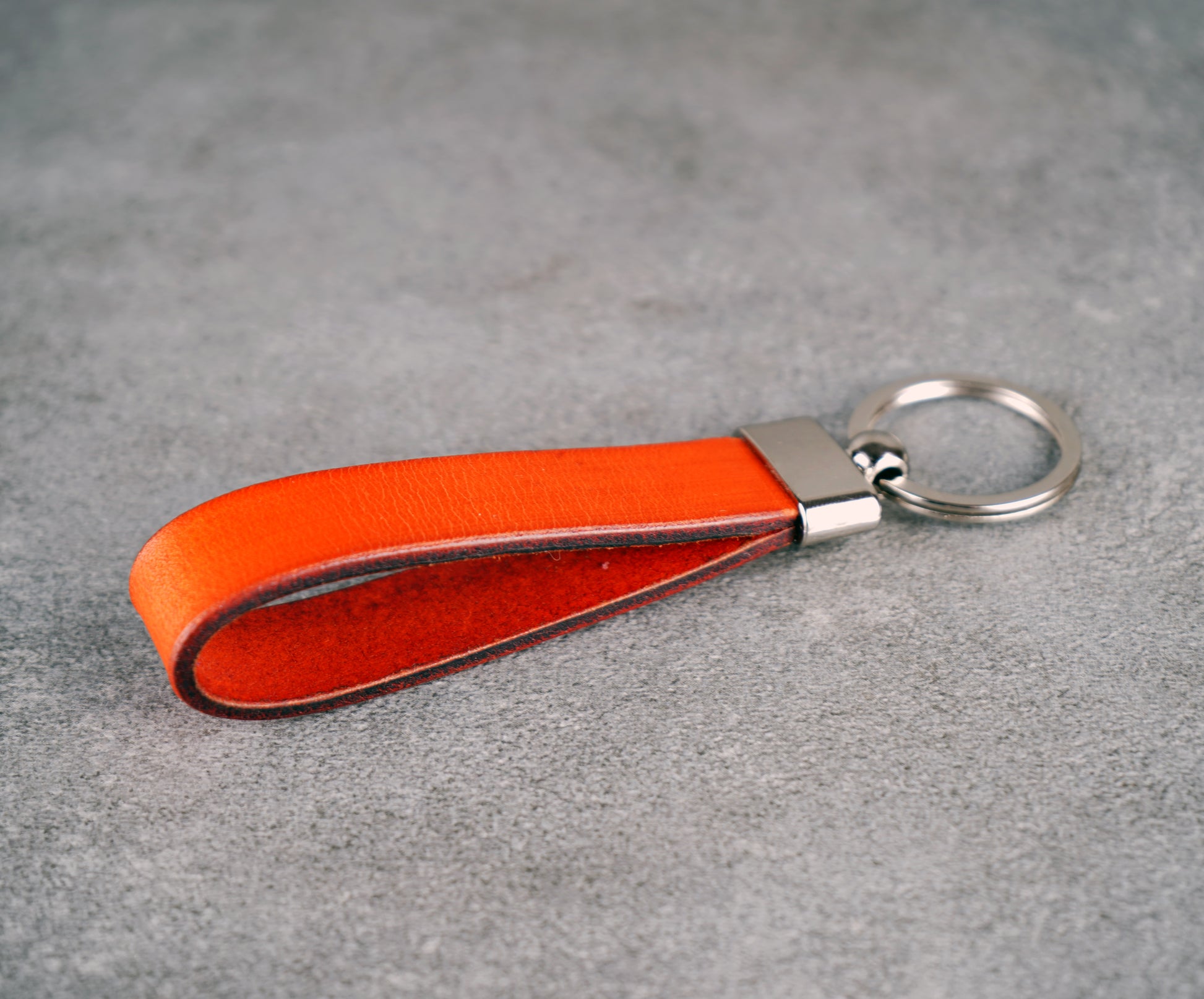 Orange leather keychain with a metal key ring on a gray surface