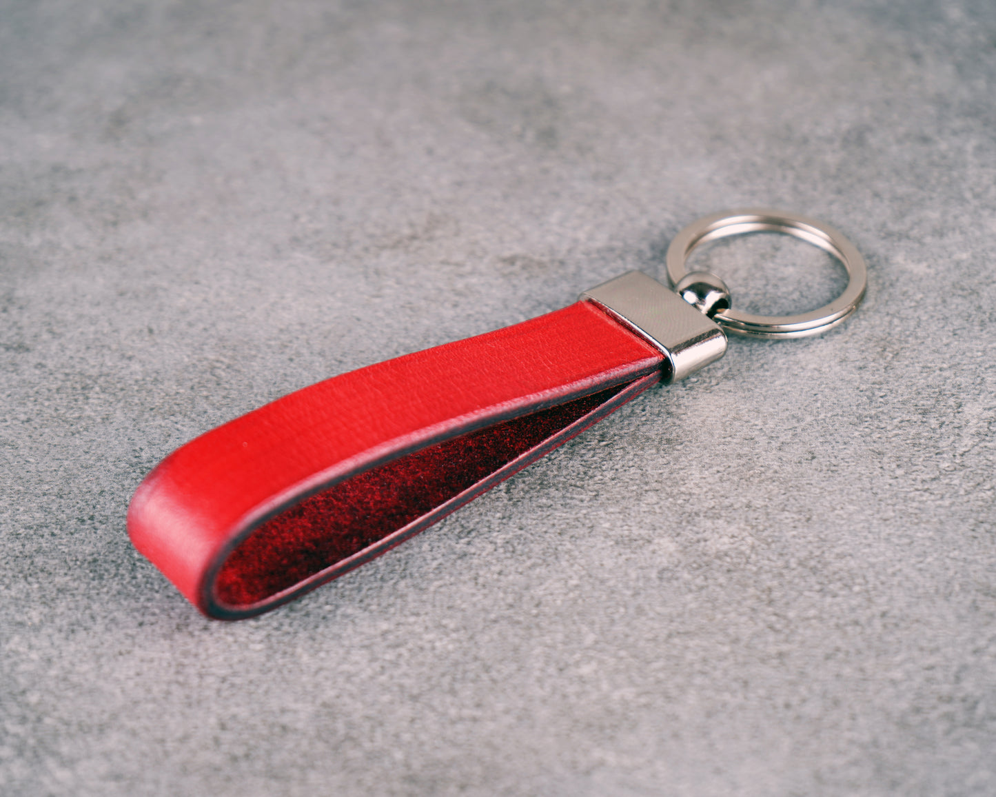 Red leather keychain on a gray surface