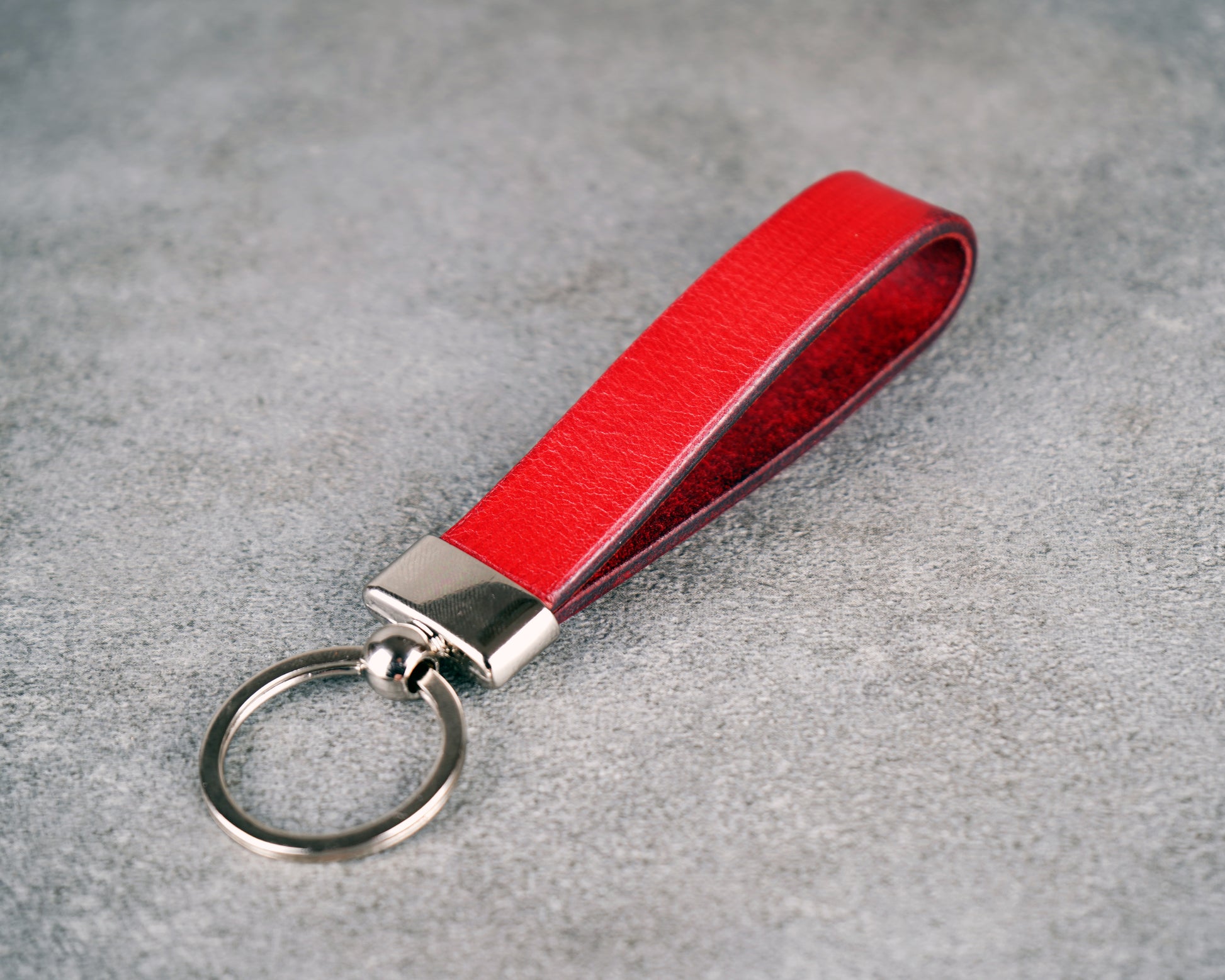 Red leather keychain with silver ring on a gray surface