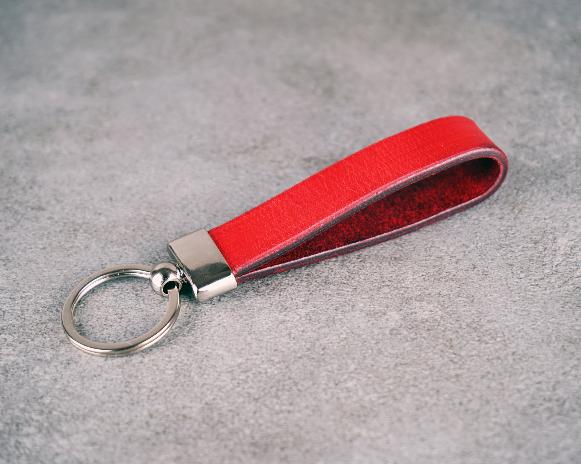 Red leather keychain with silver ring on a gray surface