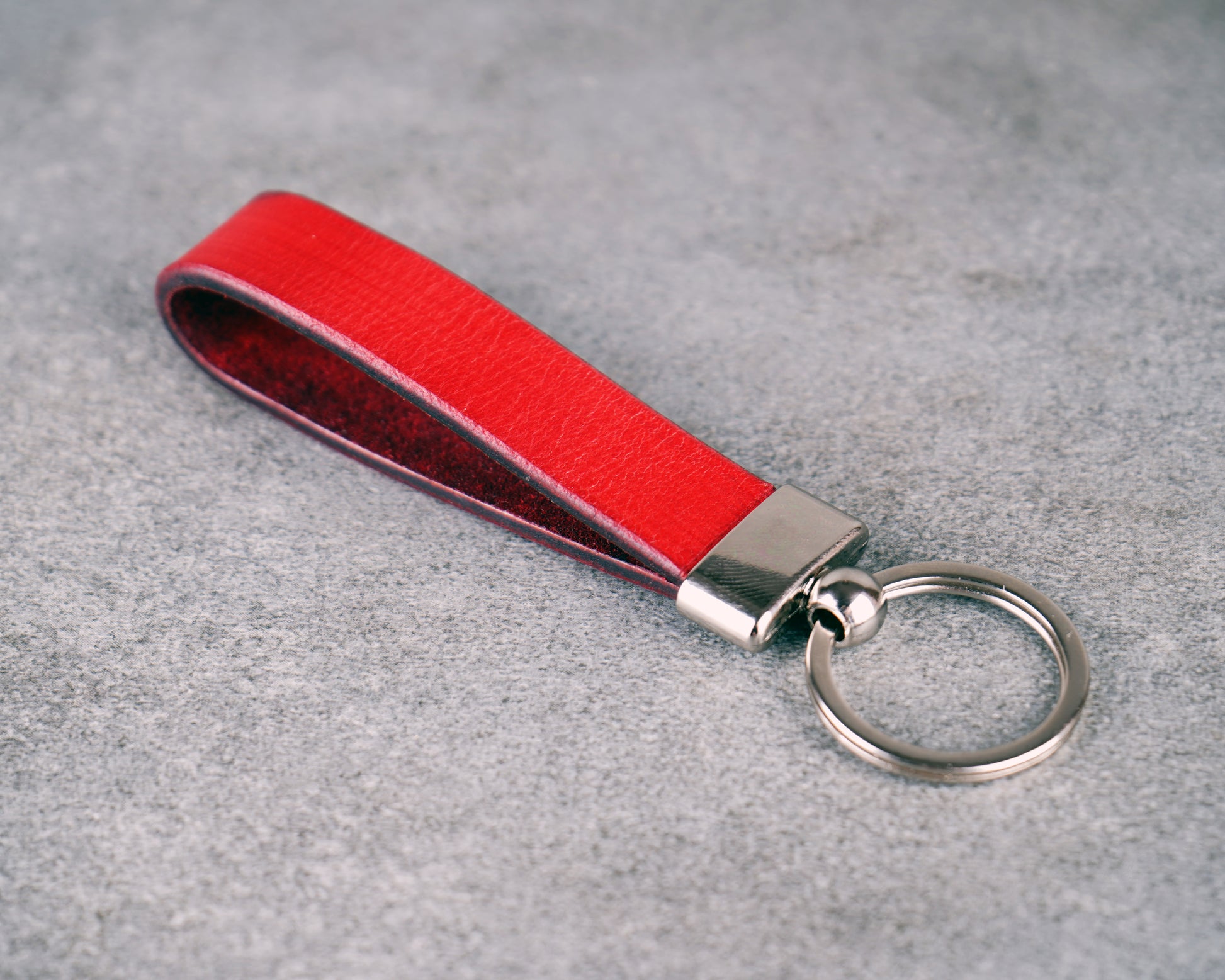 Red leather keychain with silver clasp on a gray surface
