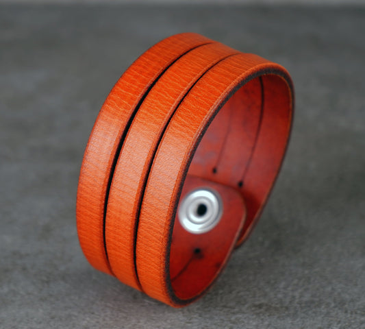 Orange leather bracelet with a silver clasp on a gray background