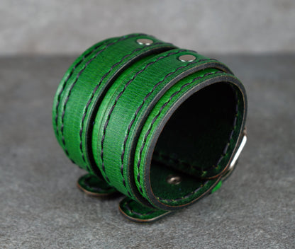 Green leather cuff bracelet on a gray surface