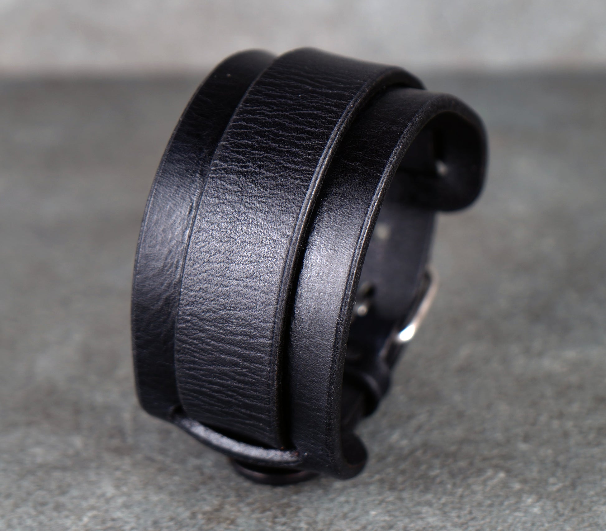 Black leather bracelet on a gray surface