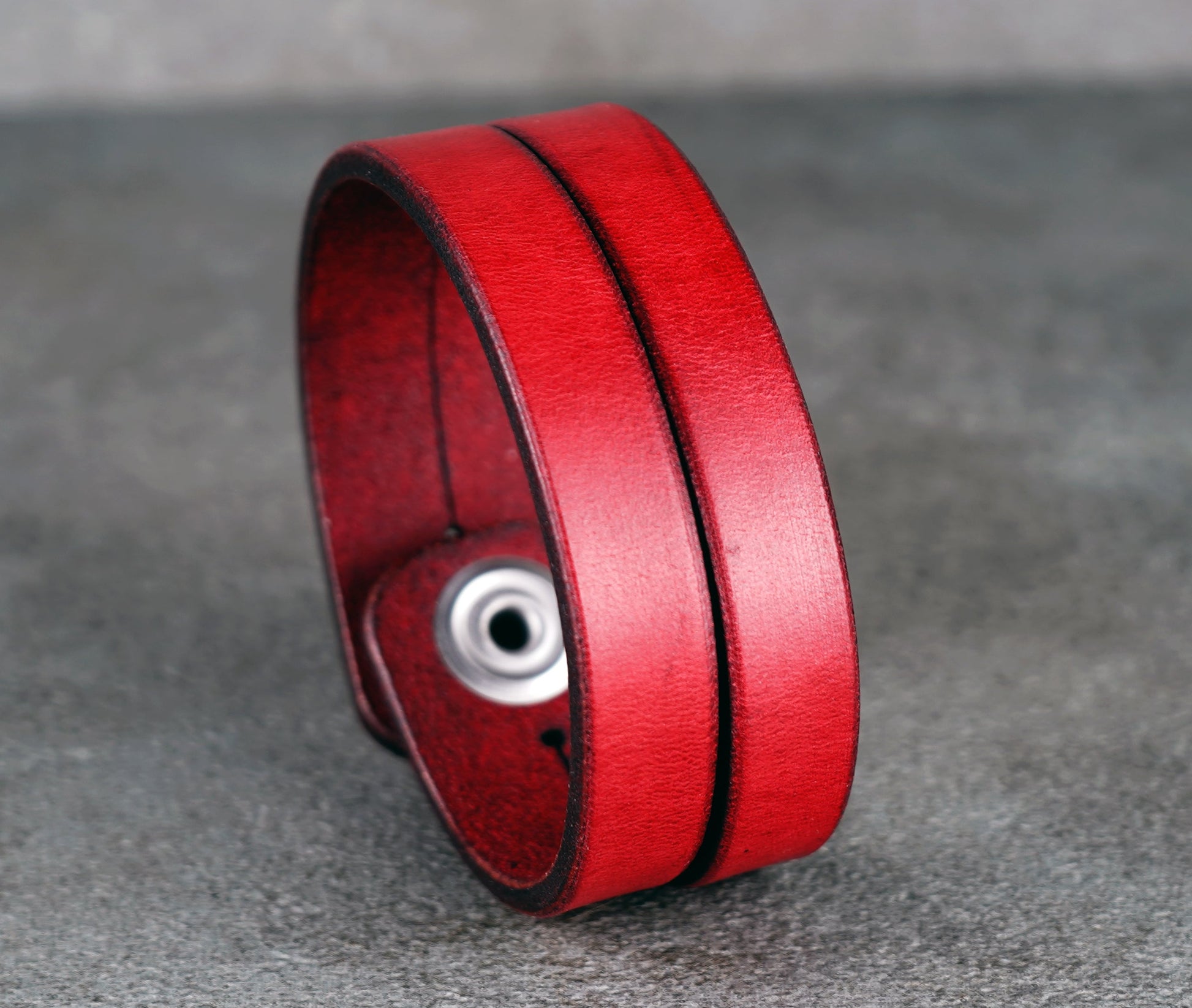 Red leather bracelet on a gray surface