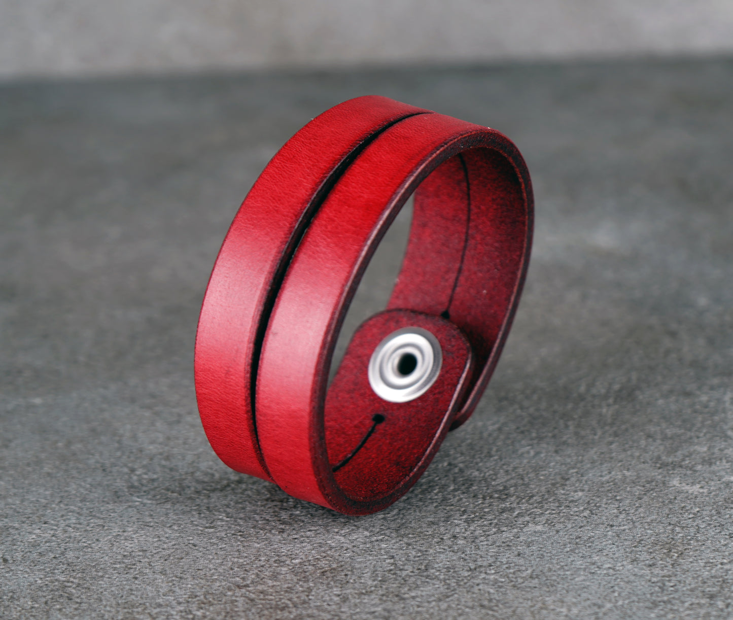 Red leather bracelet on a gray surface