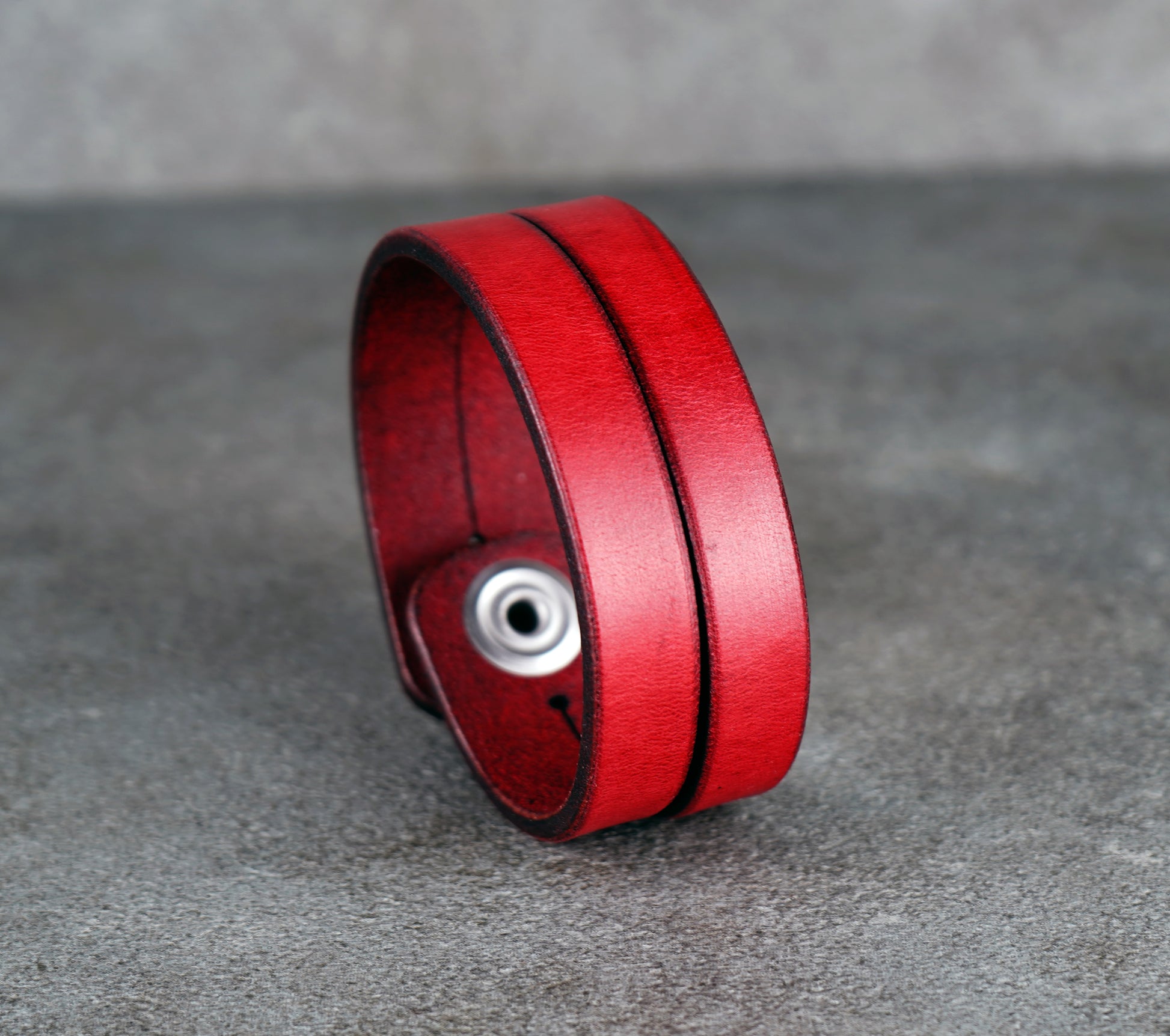 Red leather bracelet on a gray surface