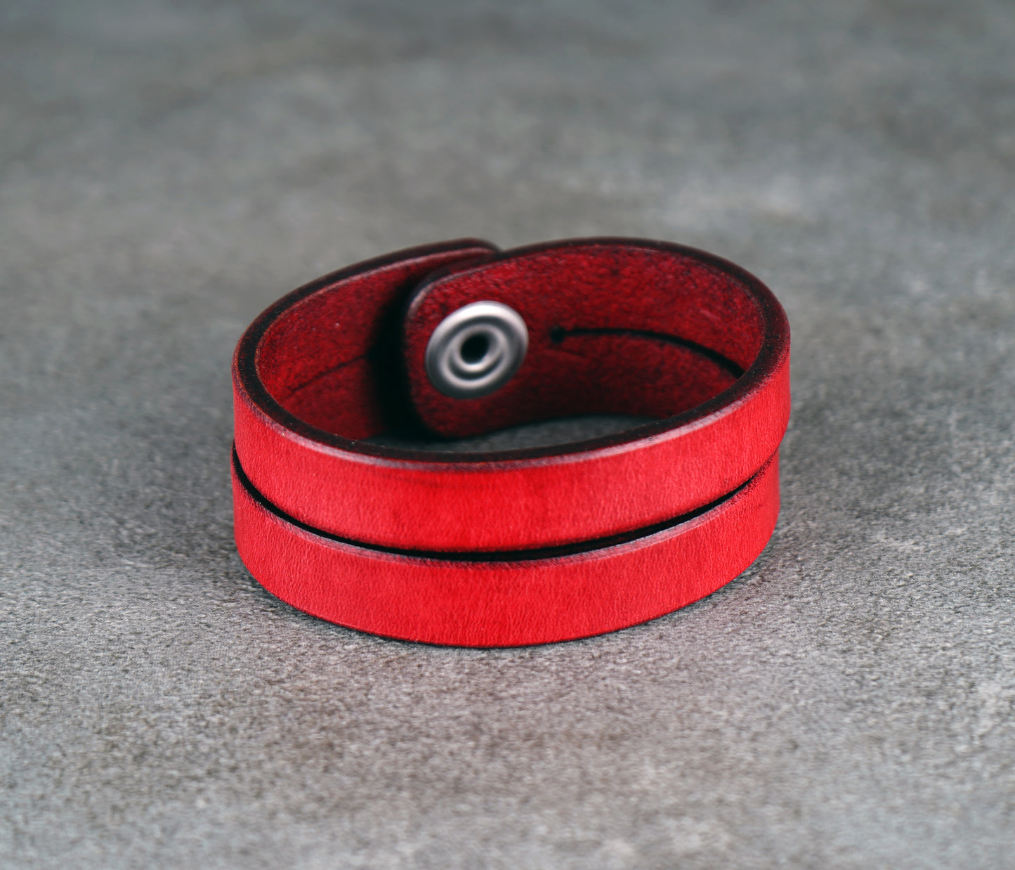 Red leather bracelet on a gray surface