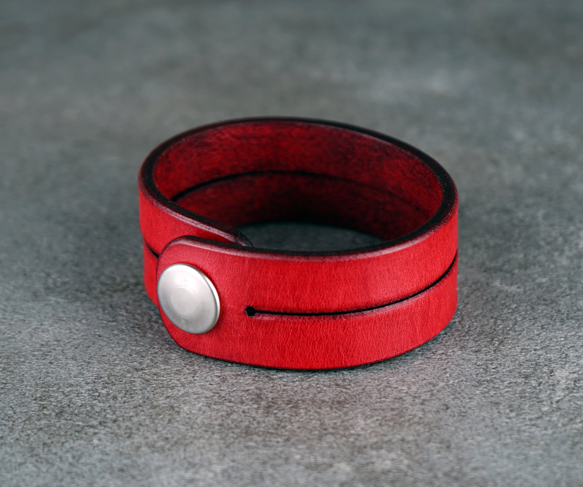 Red leather bracelet on a gray surface