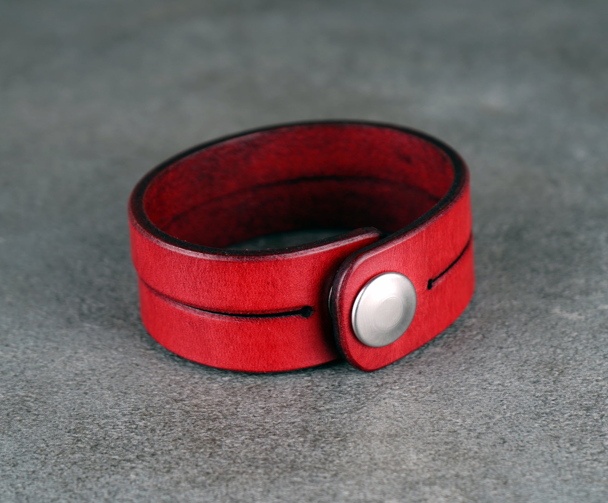 Red leather bracelet on a gray surface