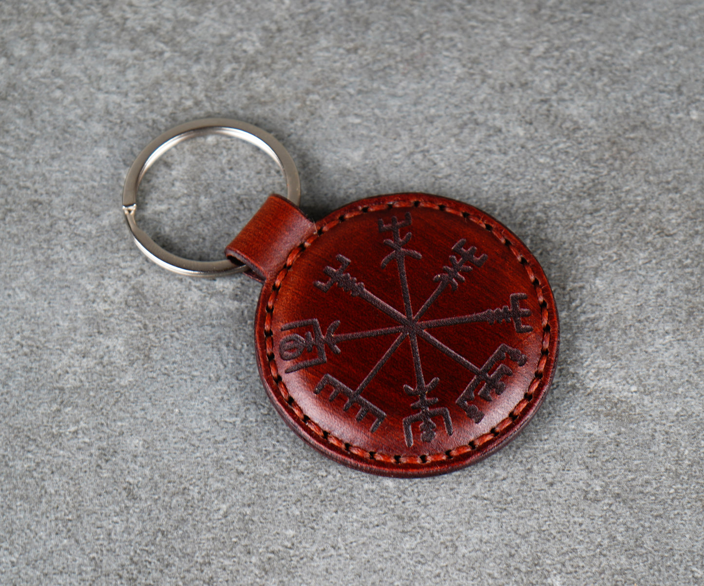 Brown leather keychain with a circular design on a gray surface