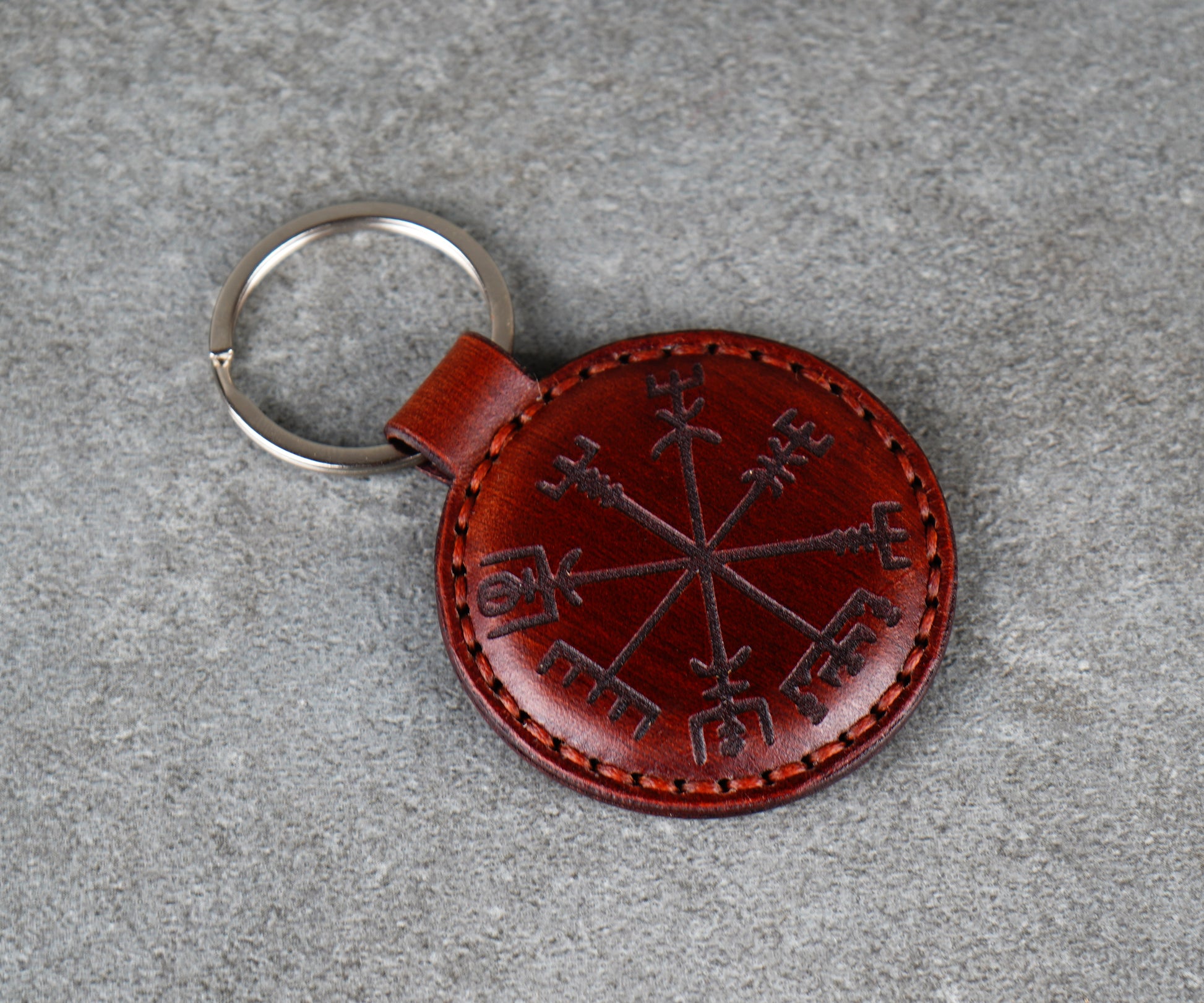 Brown leather keychain with a circular design on a gray surface