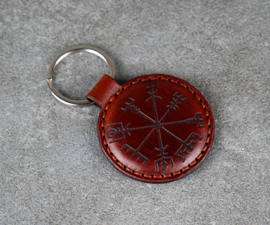 Brown leather keychain with a circular design on a gray surface