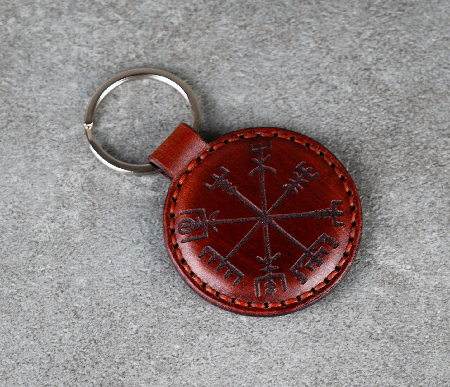 Brown leather keychain with embroidered design on a gray surface