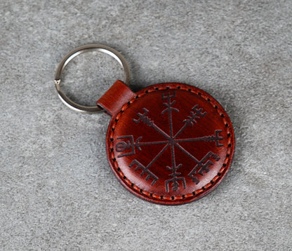 Brown leather keychain with embroidered design on a gray surface