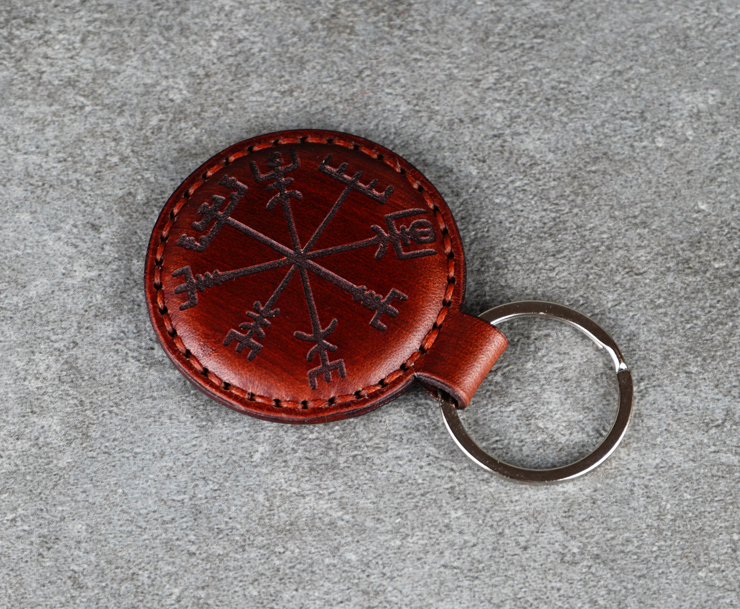 Brown leather keychain with Viking Runes design on a gray surface