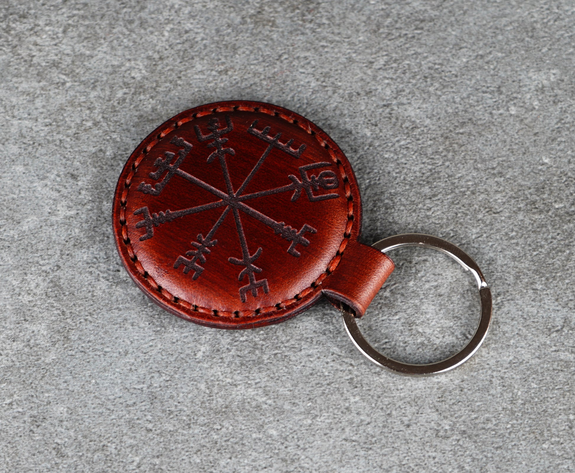 Brown leather keychain with Viking Runes design on a gray surface