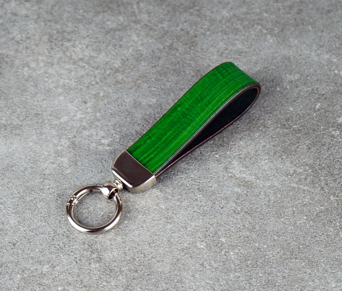 Green keychain with metallic accent on a gray surface