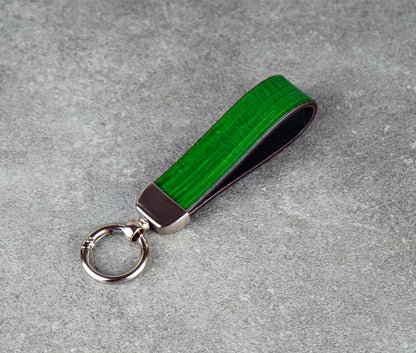 Green keychain with metallic accent on a gray surface