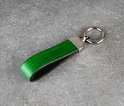 Green keychain with silver clip on a gray surface