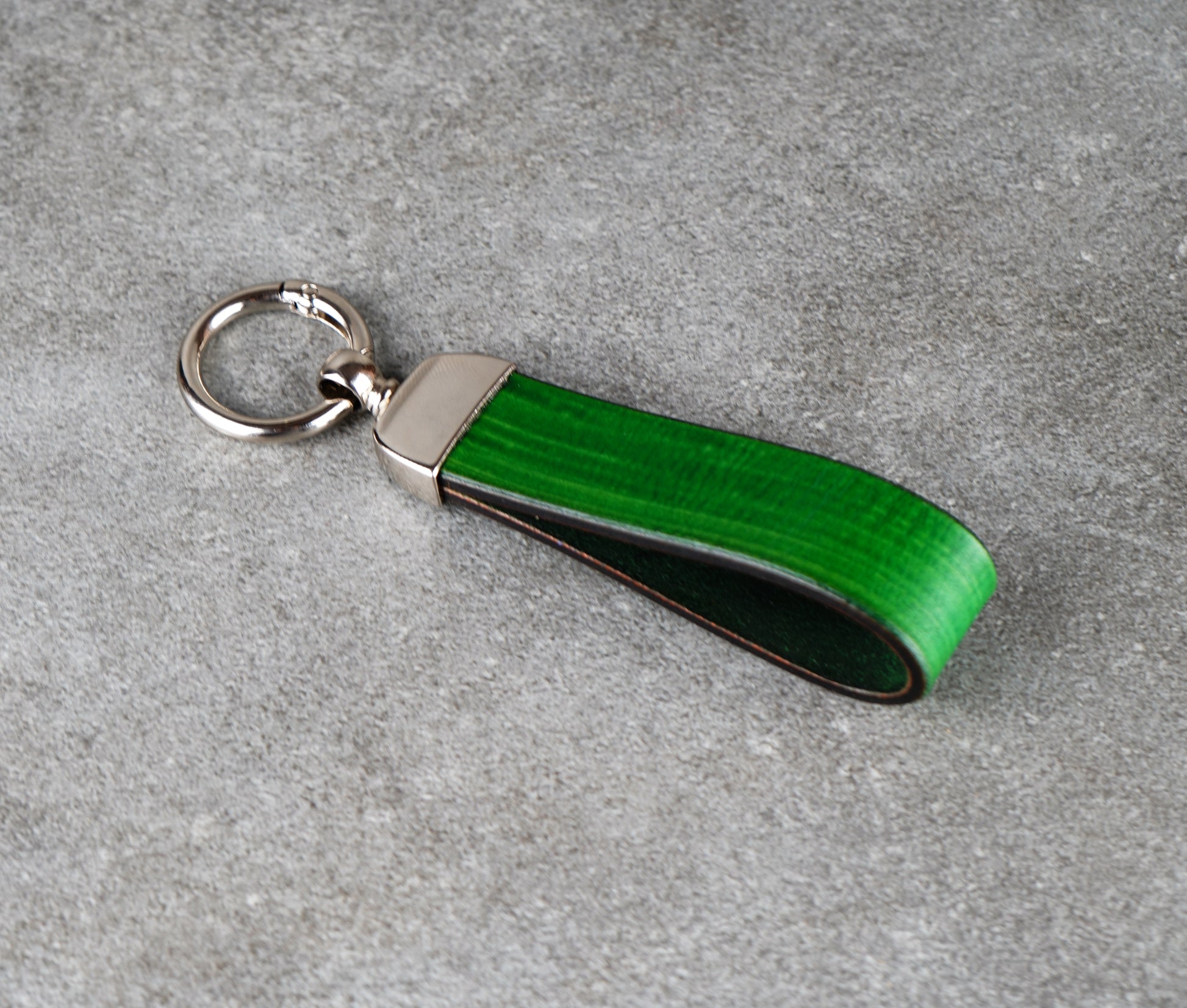 Green leather keychain with silver ring on a gray surface