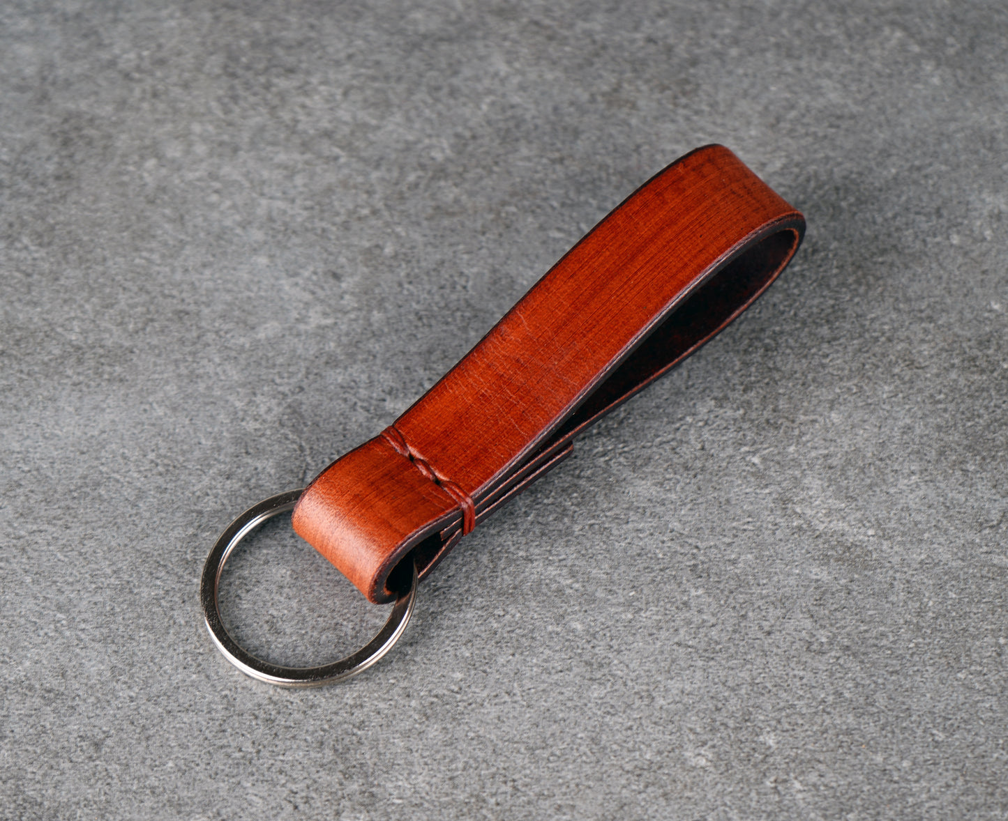 Brown leather keychain with a metal ring on a gray surface
