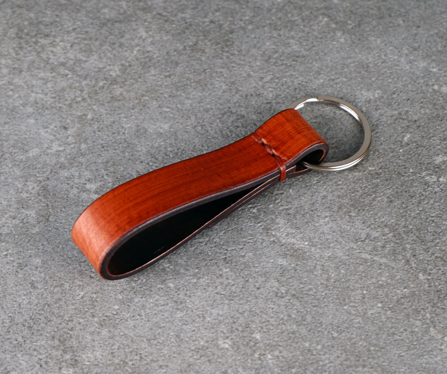 Brown leather keychain on a gray concrete surface