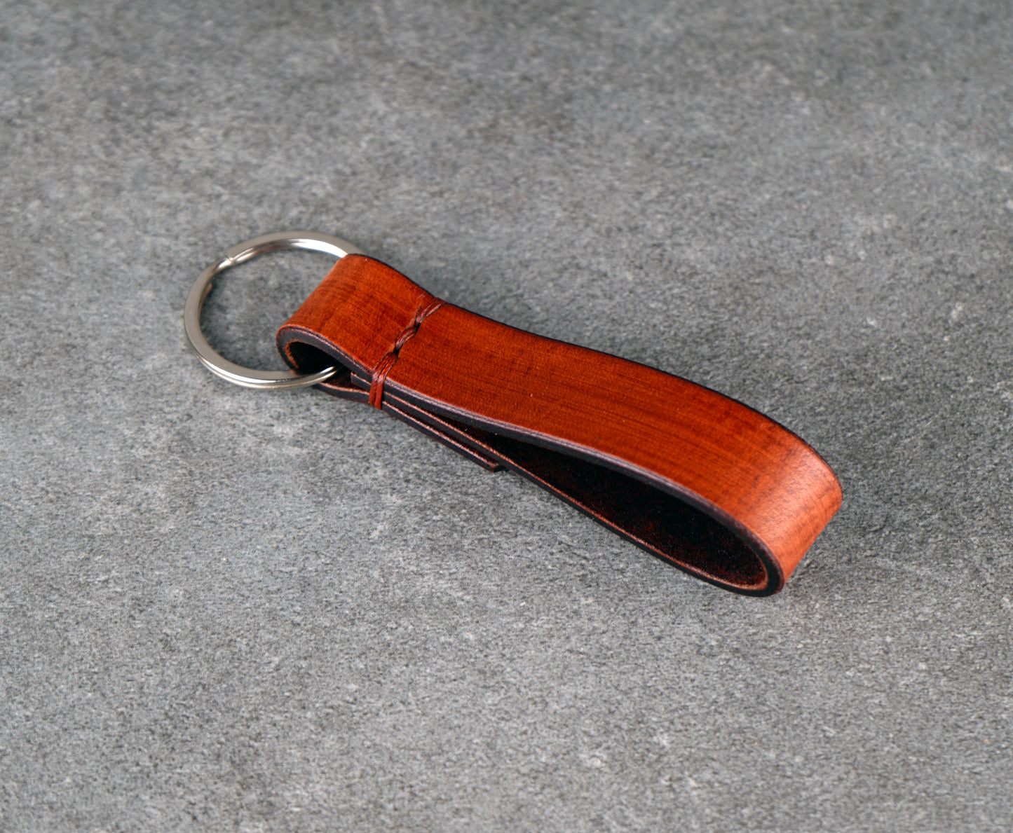 Brown leather keychain on a gray surface